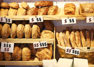 Various loaves of bread for sale with price tags next to each type. 