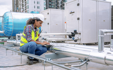 Female HVAC technician repairing rooftop HVAC unit. 