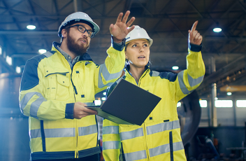 Male and female engineers talking in industrial setting. 