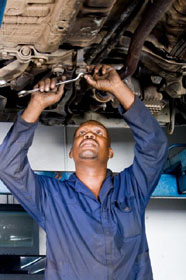 Mechanic working on vehicle overhead